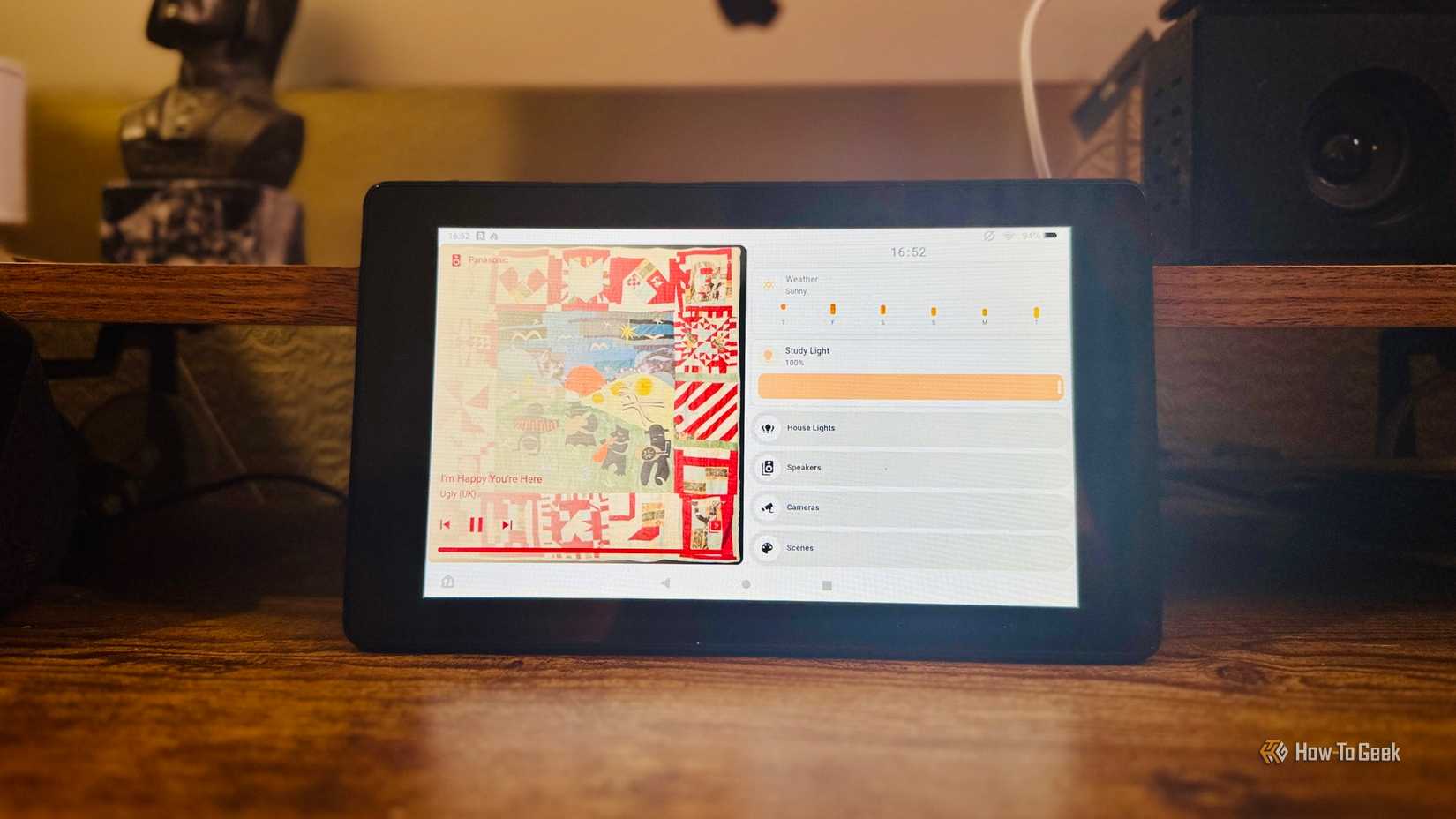 A tablet leaning on a shelf between a figurine and a smart speaker showing a Home Assistant dashboard.