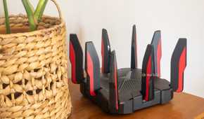 TP-Link's Archer GX90 Wi-Fi 6 router sitting on a table next to a plant.