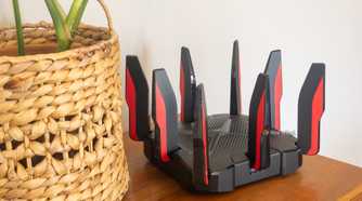 TP-Link's Archer GX90 Wi-Fi 6 router sitting on a table next to a plant.