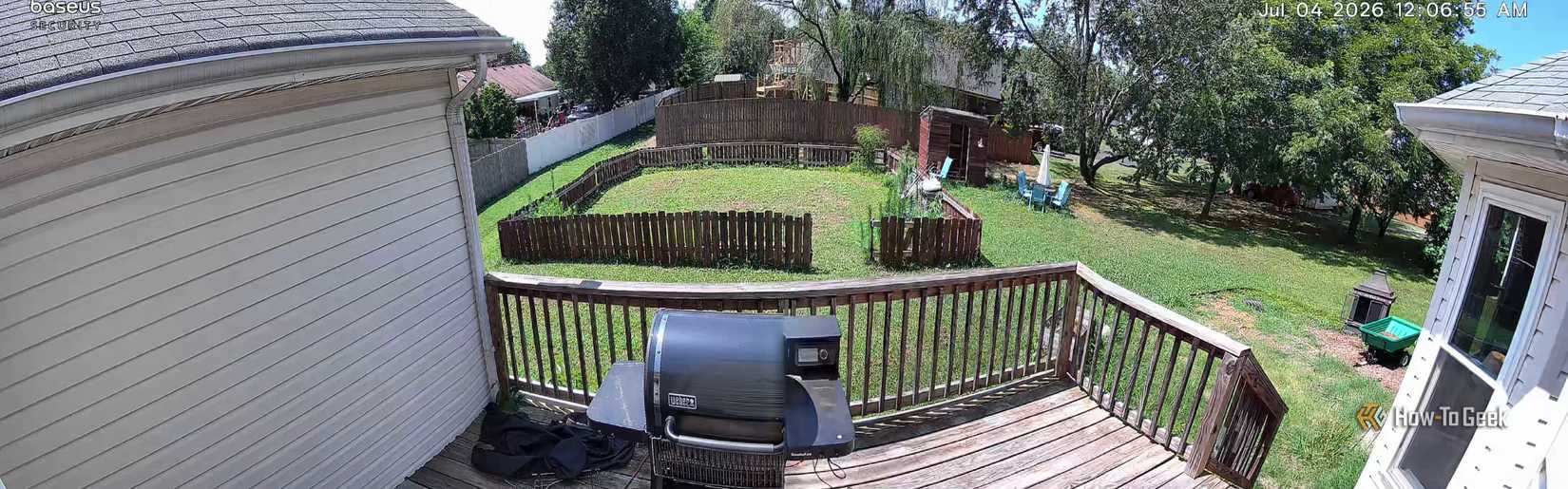 A picture of a back yard showing a fenced in area and smoker on a deck.