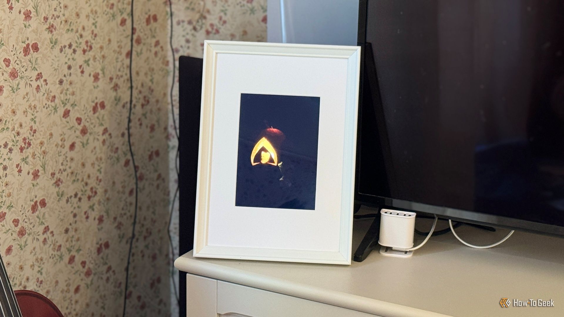 Raspberry Pi photo frame made from an iPad 2 panel displaying a glowing jack o lantern in a dark room.