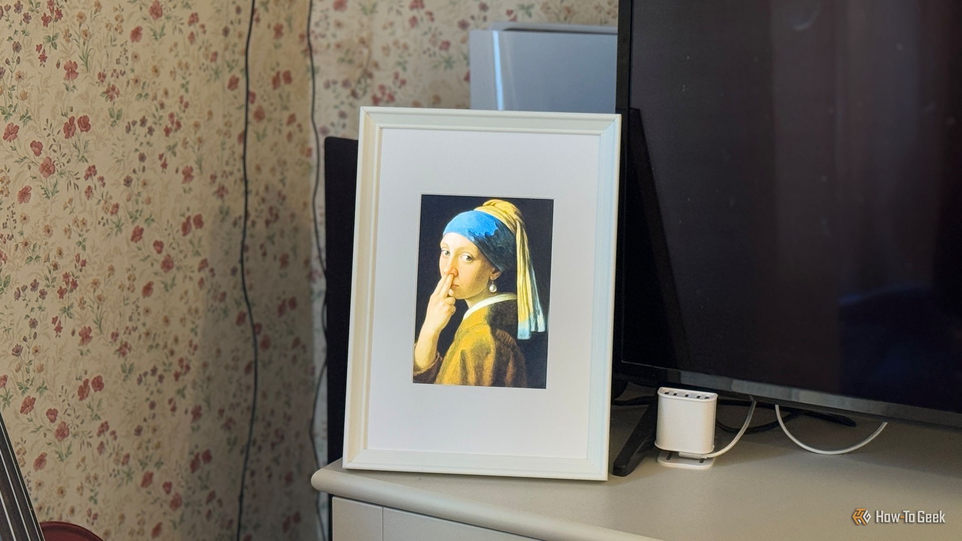 Raspberry Pi photo frame made from an iPad 2 panel displaying a parody of Girl with a Pearl Earring with a finger in the nose.