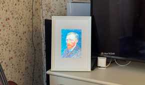 Raspberry Pi photo frame made from an iPad 2 panel displaying a Van Gogh self portrait beside a TV.