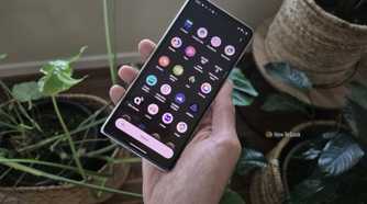Hand holding a Motorola Razr Fold in front of house plants.
