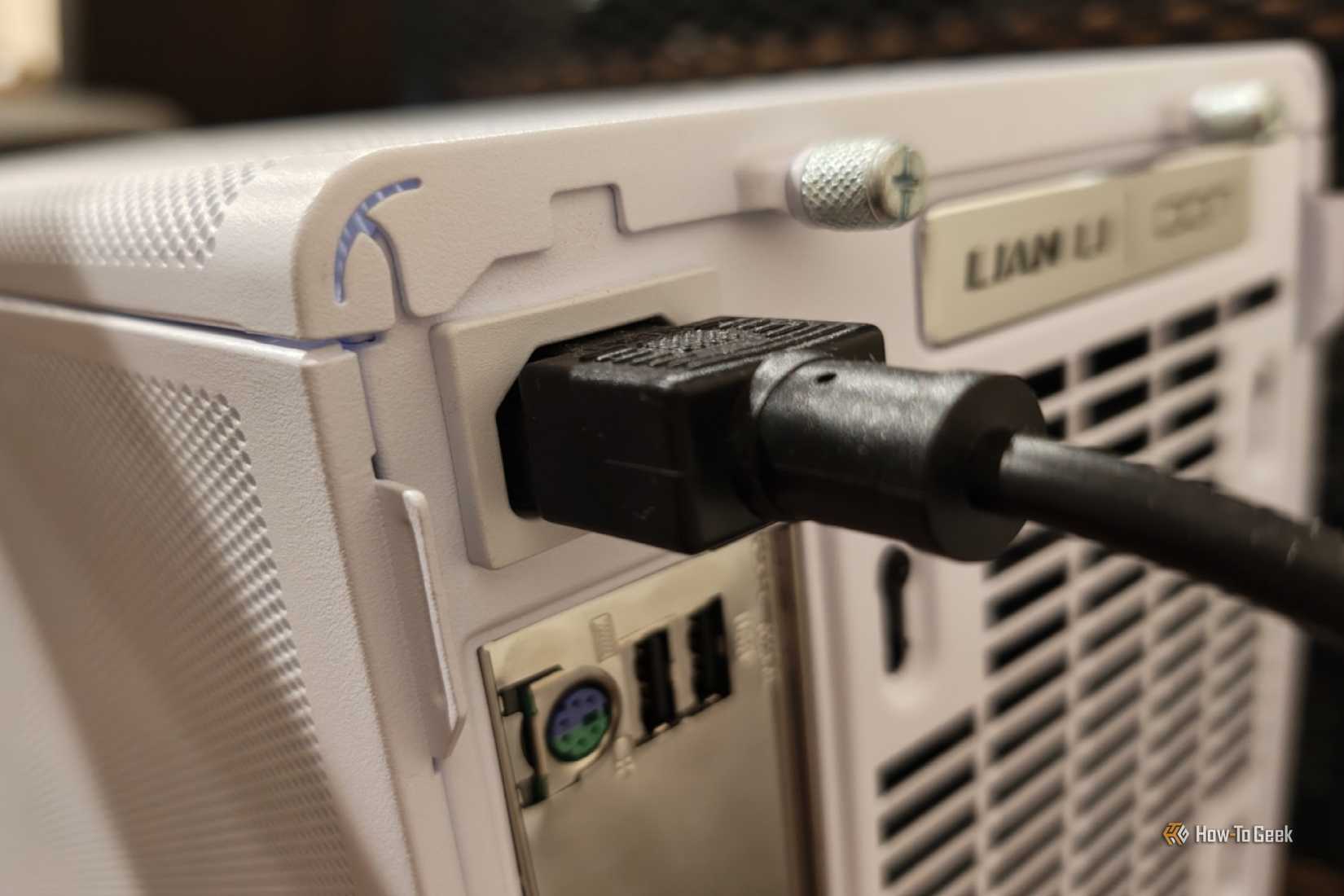A power cable plugged into the back of a desktop PC.