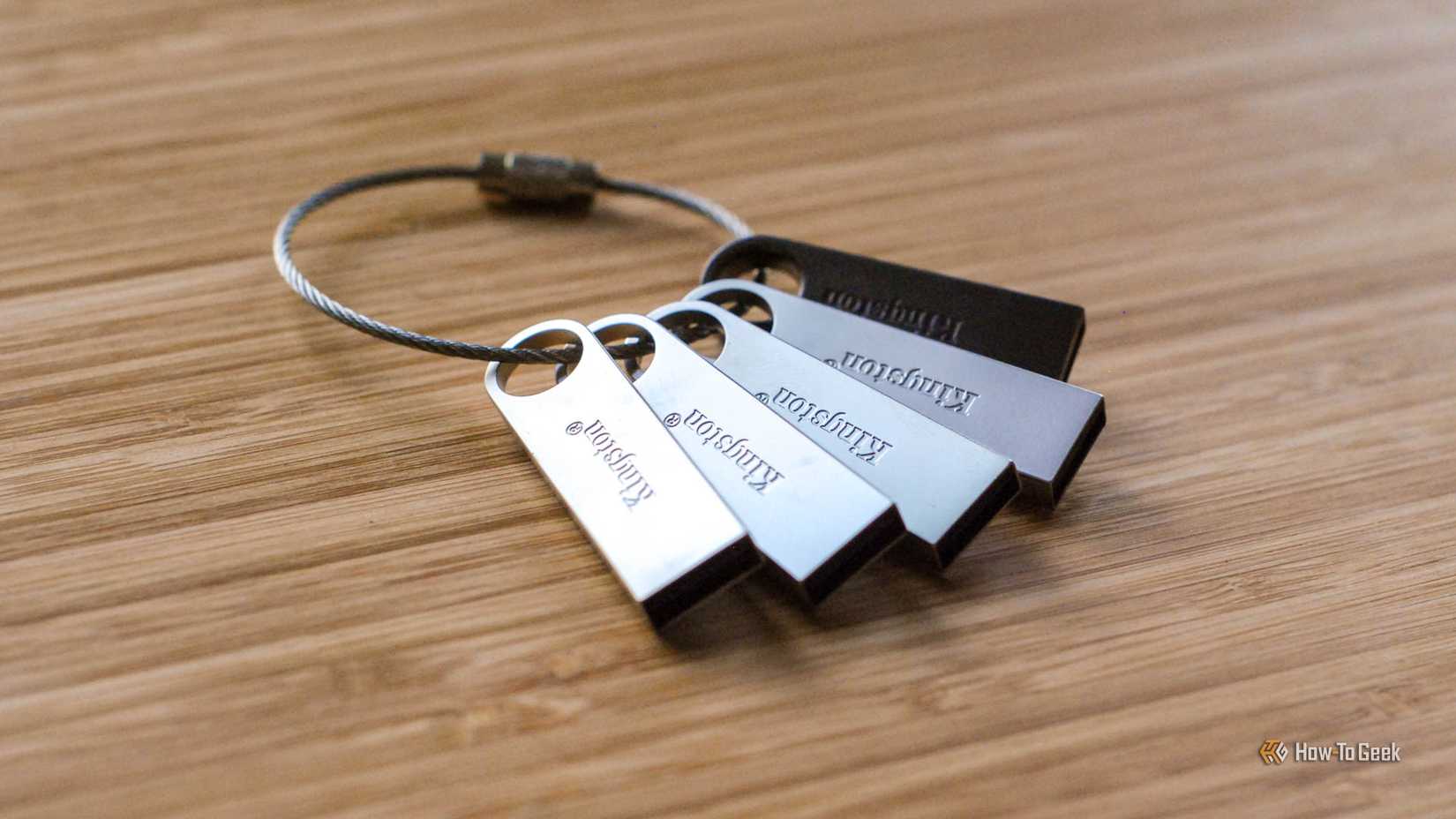 A key ring with five Kingston USB thumb drives on a wooden surface.