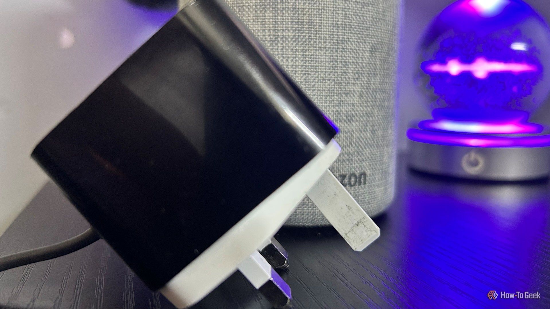 An Amazon Echo Gen 2 with its mains plug diconnected and placed on the desk next to it.