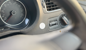 An NFC tag stuck to the dashboard of a car.