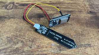 Capacitive soil moisture sensor and ESP32 development board mounted in a black pin header bracket photographed upside down.