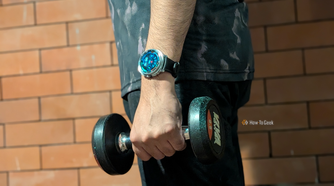 My hand holding a dumb bell in the gym with a dense health data watchface on my Galaxy Watch 8 Classic.