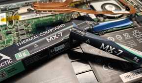 Arctic MX-7 thermal paste next to a disassembled laptop.