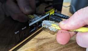 Person connecting an Ethernet cable to the Netgear Nighthawk MK93S main router.