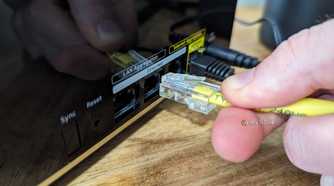 Person connecting an Ethernet cable to the Netgear Nighthawk MK93S main router.