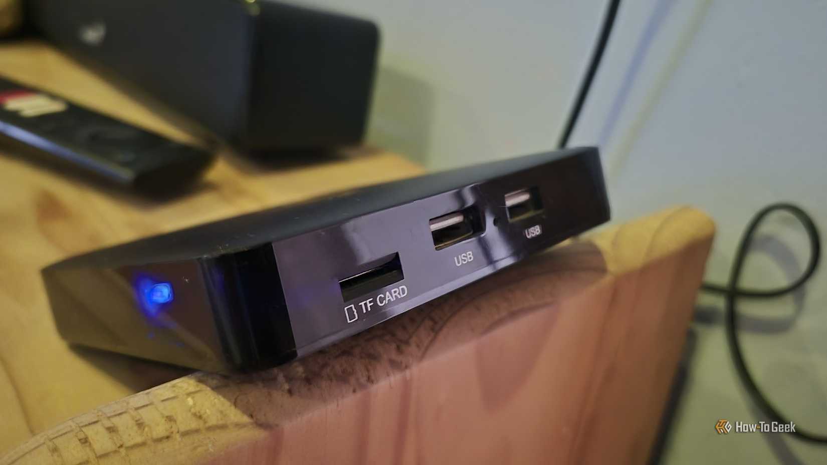 Ematic dv8235 ஆண்ட்ராய்டு டிவி பெட்டி ஒரு அலமாரியின் விளிம்பில் சமநிலைப்படுத்தப்பட்டுள்ளது 
