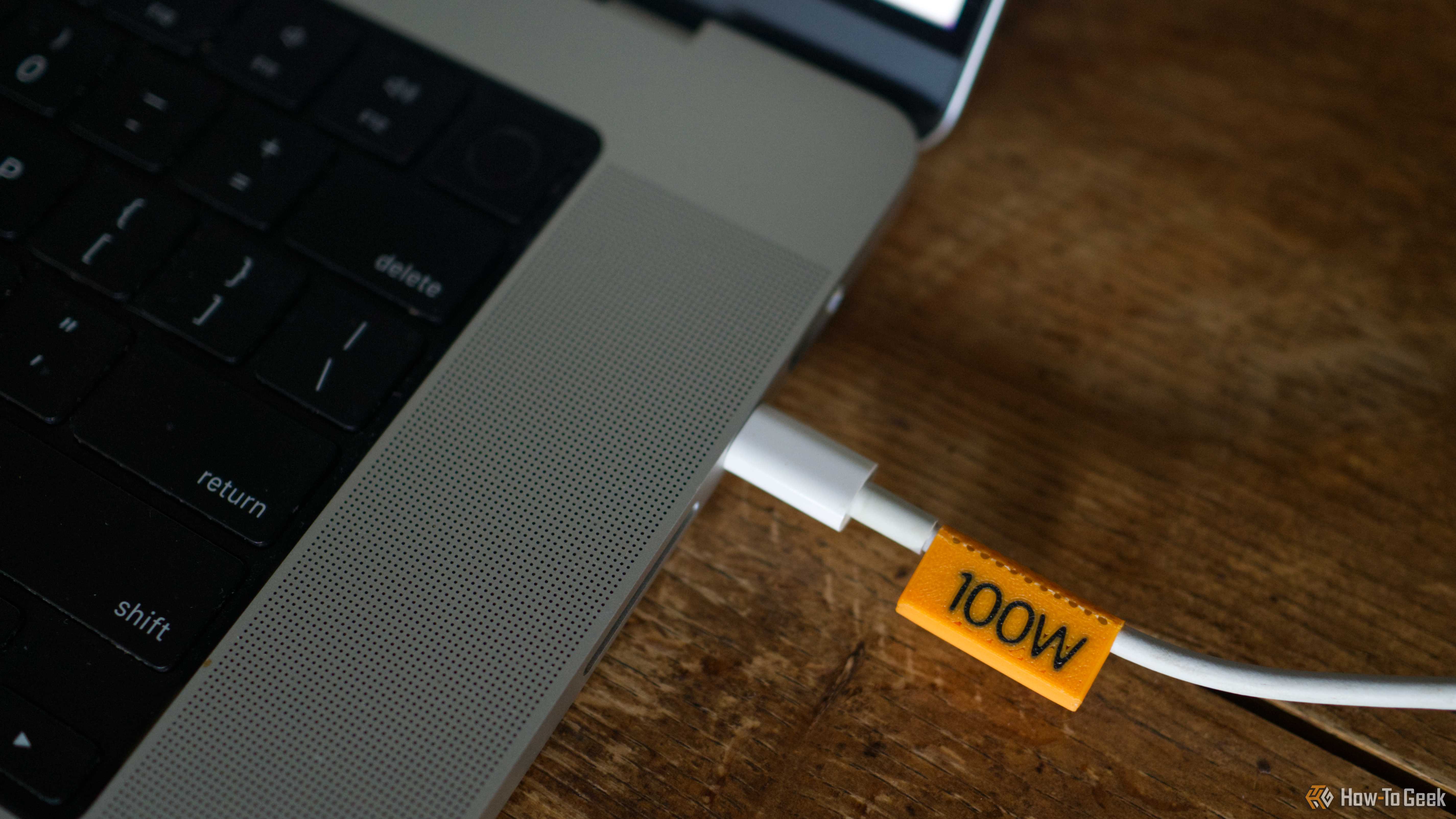 3D printed 100W orange cable clip plugged into a laptop.