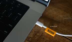 3D printed 100W orange cable clip plugged into a laptop.