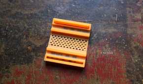 3D printed 100W orange cable clip upside down.