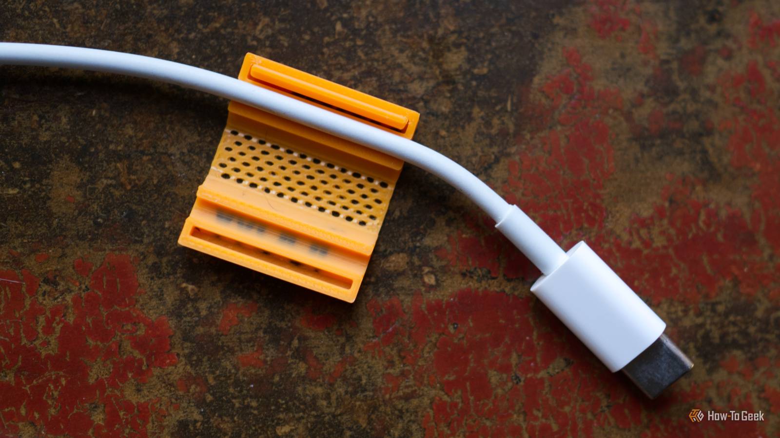 3D printed 100W orange cable clip with a thin cable.