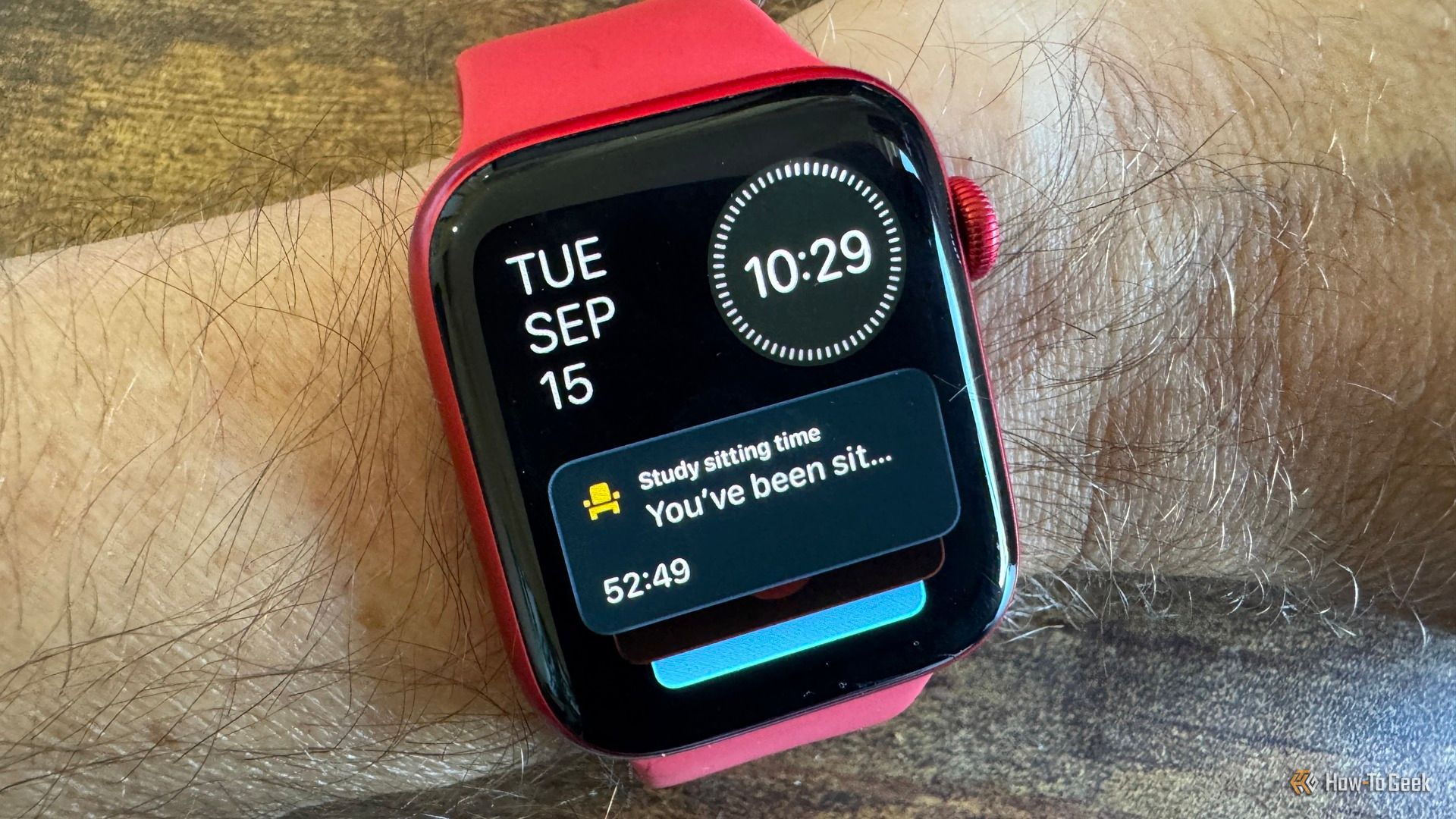 Apple Watch on wrist showing a Live Activity notification tracking desk sitting time.