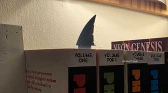 Shark-fin bookmarks protruding from several numbered book volumes on a shelf.