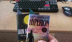 Dan Simmons’ Hyperion held in front of another book, both fitted with shark-fin bookmarks.