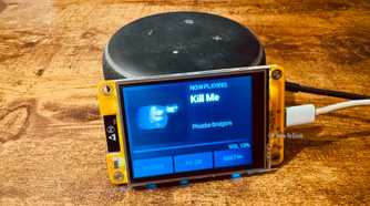 Cheap Yellow Display mounted on an Echo speaker showing a Now Playing screen for Kill Me by Phoebe Bridgers.