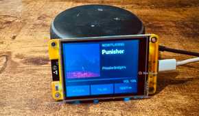 Cheap Yellow Display mounted on an Echo speaker showing a Now Playing screen for Punisher by Phoebe Bridgers with pause and skip controls.
