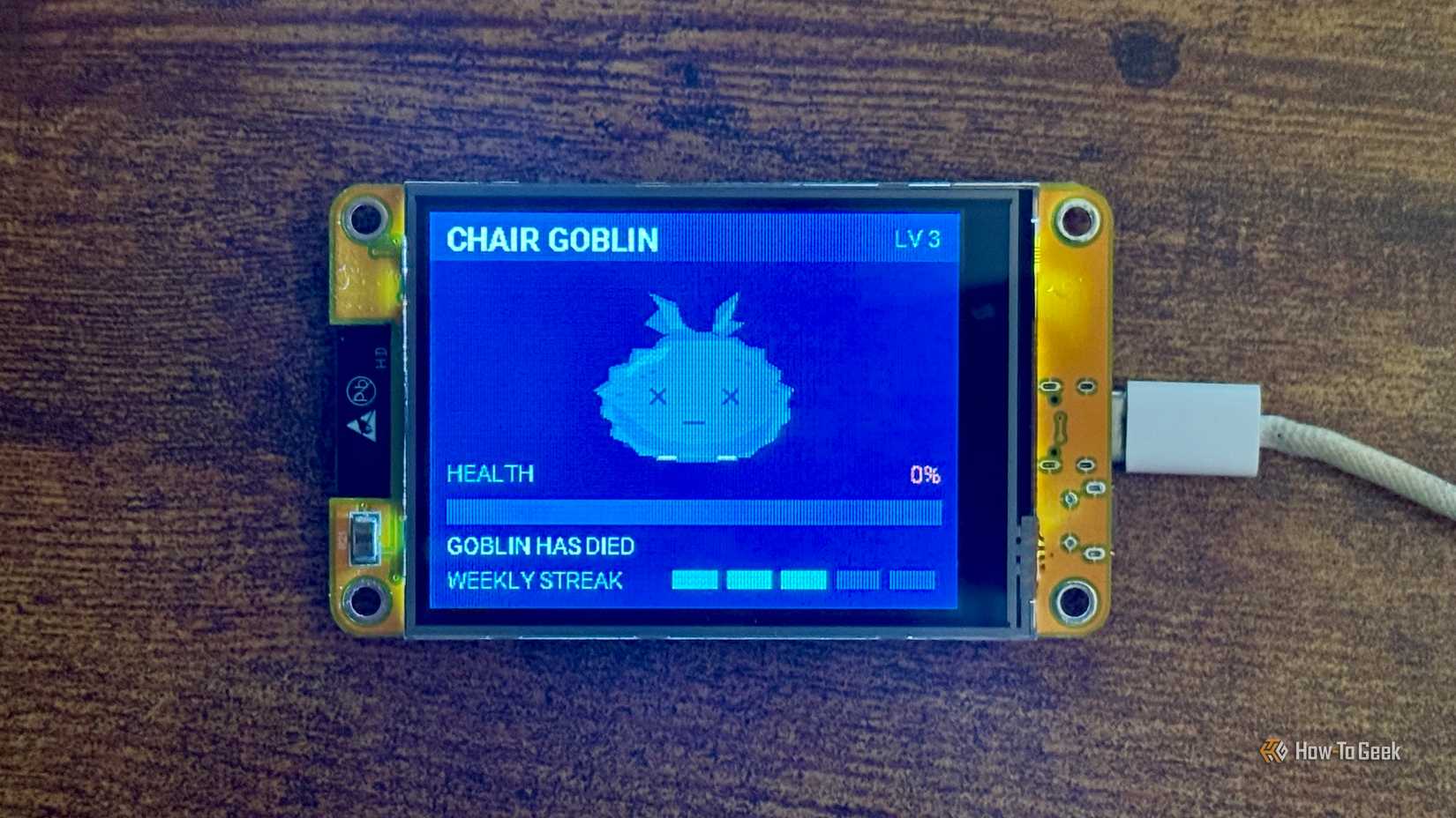 Cheap Yellow Display Tamagotchi showing Chair Goblin at level 3 with 0 percent health and the Goblin has died message.