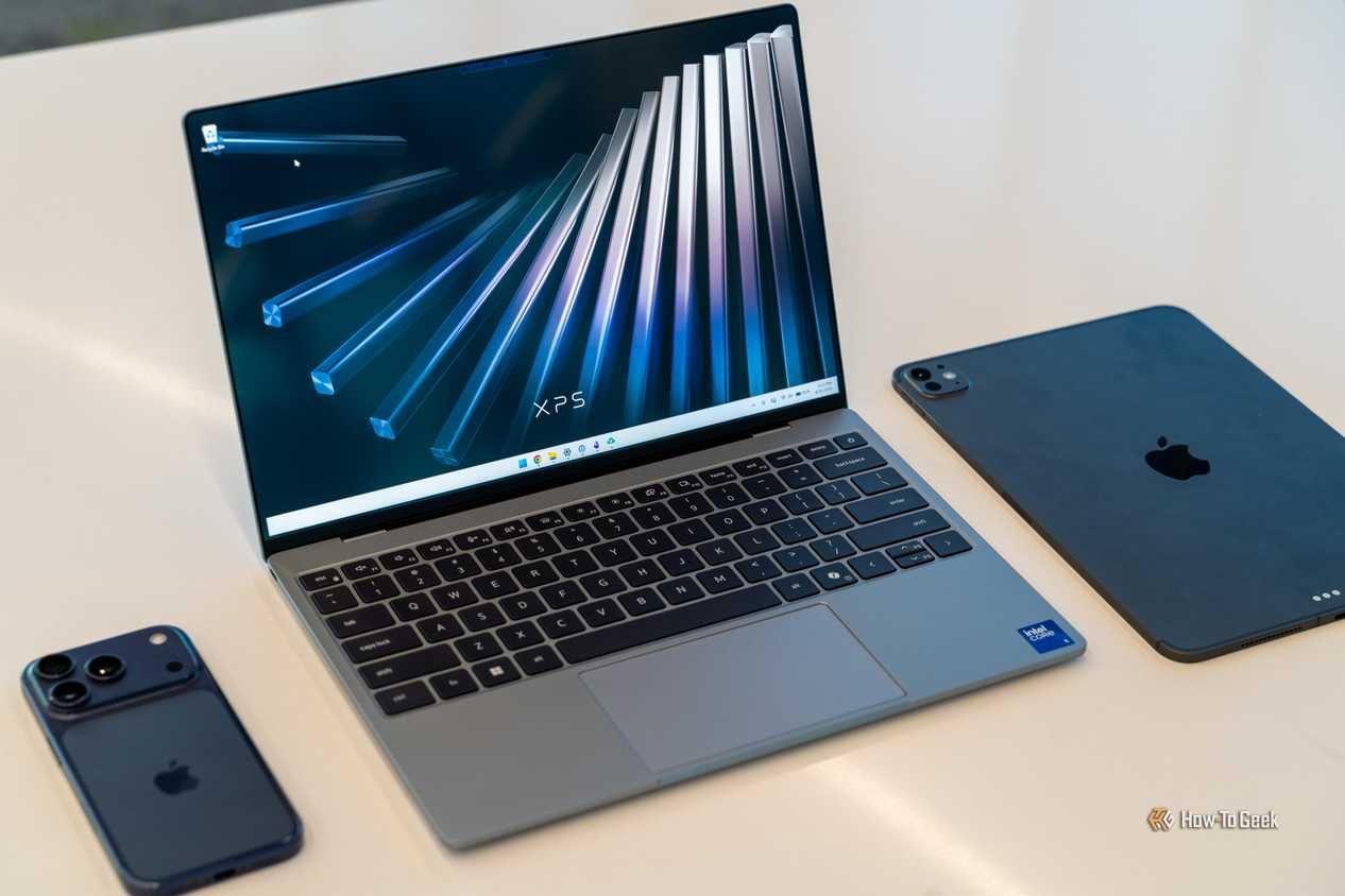 Dell XPS 13 2026 на рабочем столе рядом с iPhone и iPad Dell XPS 13 2026 на рабочем столе рядом с iPhone и iPad
