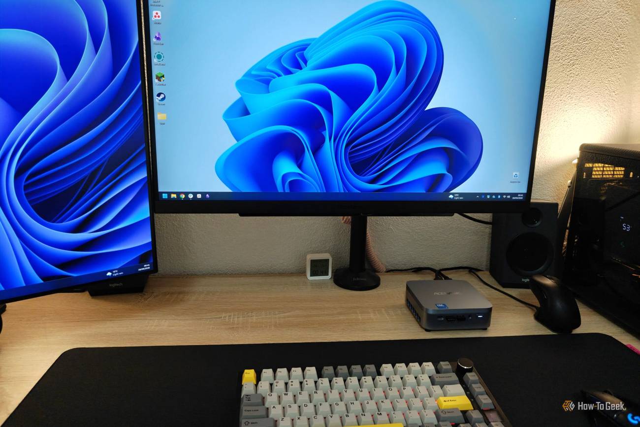 Acemagic K5 mini PC a sou yon biwo ak periferik ak monitè konekte.