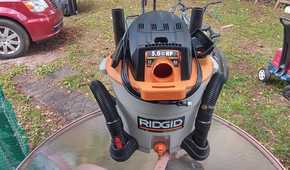 Photo of a Risgid wet and dry vac on a table with the cord wrapped and the hose sitting in the wheel's holders