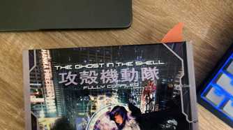 Orange shark-fin bookmark protruding from a copy of The Ghost in the Shell: Fully Compiled.