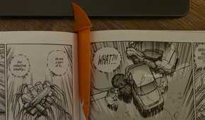 Orange shark-fin bookmark placed between the pages of an open manga book.