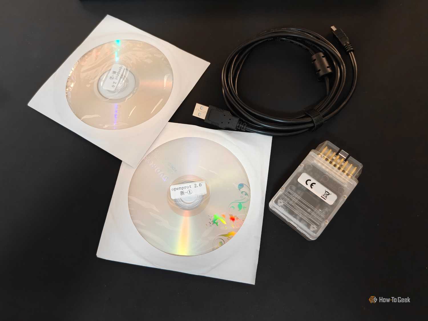 A Tactrix OpenPort 2.0 OBD-II interface with a USB cable, and software discs.