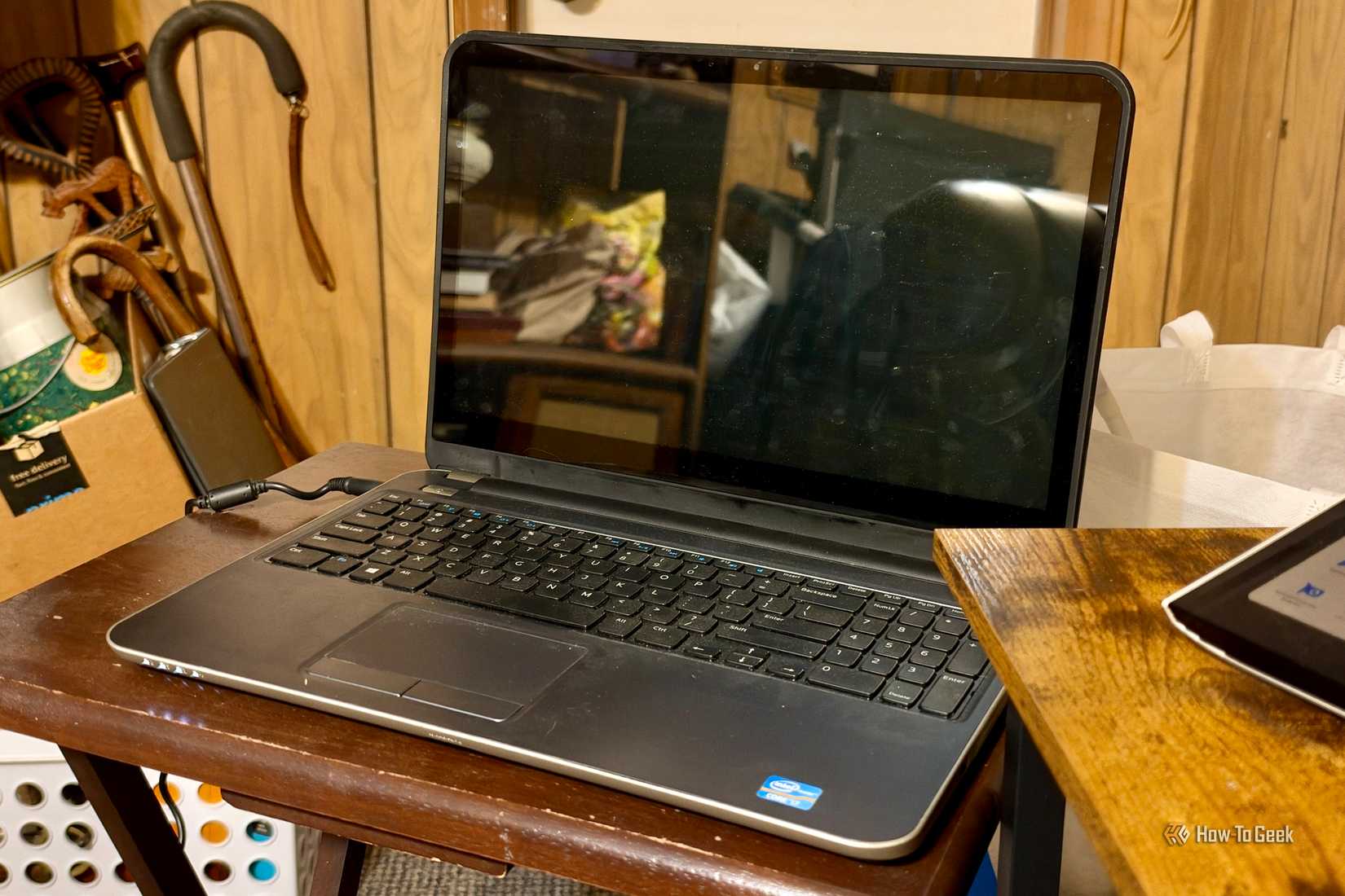 Old laptop with its screen off on a wooden foldable table.