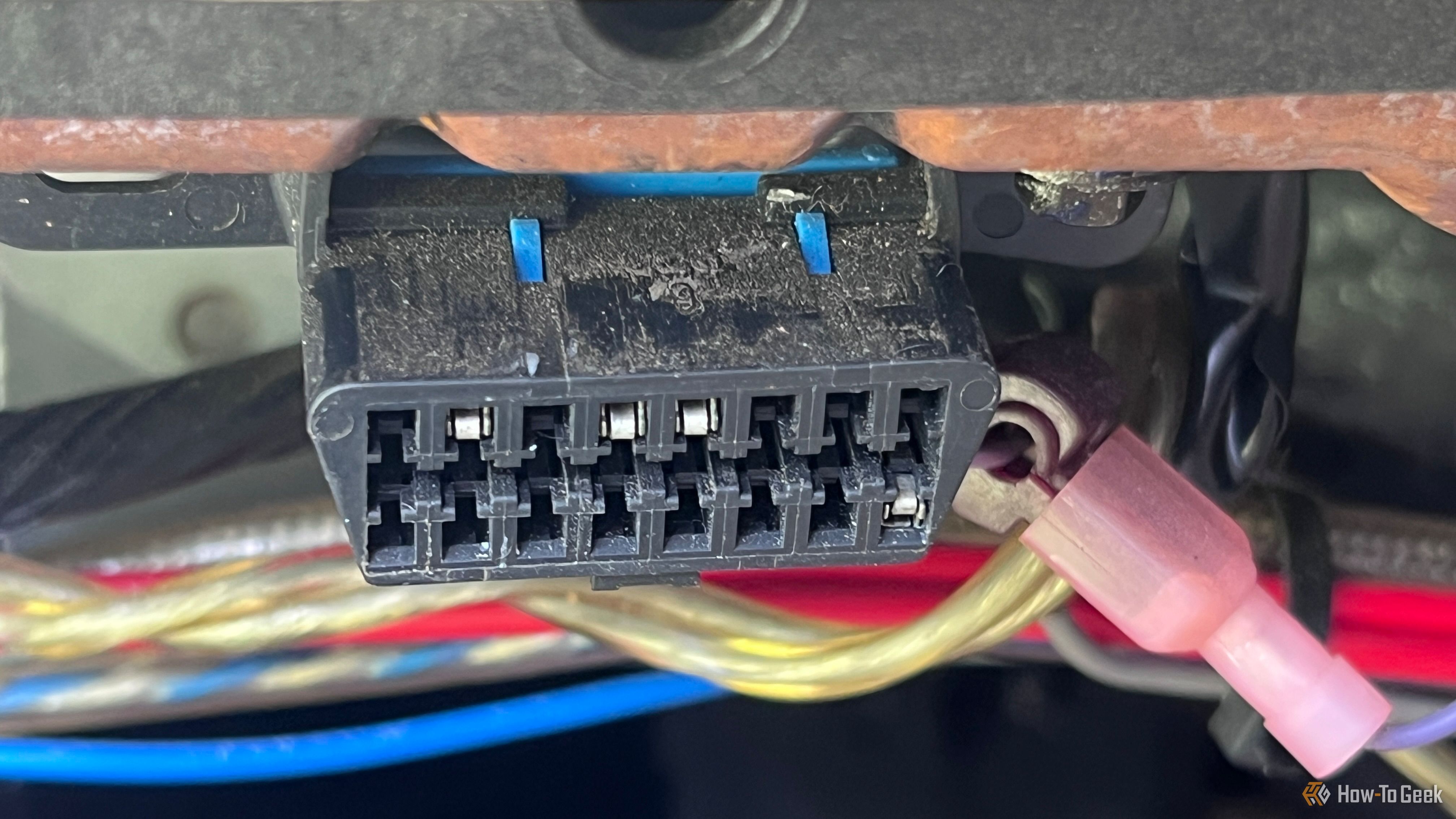An OBD-II diagnostic port under the dashboard of a vehicle.