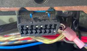 An OBD-II diagnostic port under the dashboard of a vehicle.