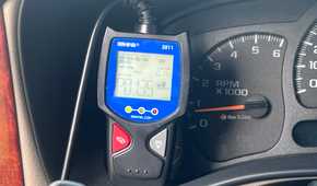An Innova 3011 OBD-II scanner displaying a trouble code beside the vehicle's gauges.