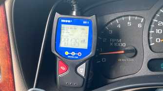 An Innova 3011 OBD-II scanner displaying a trouble code beside the vehicle's gauges.