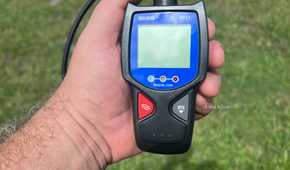 An Innova 3011 handheld OBD-II scanner held outside in the sunlight..
