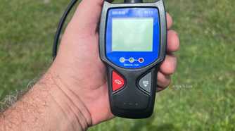 An Innova 3011 handheld OBD-II scanner held outside in the sunlight..