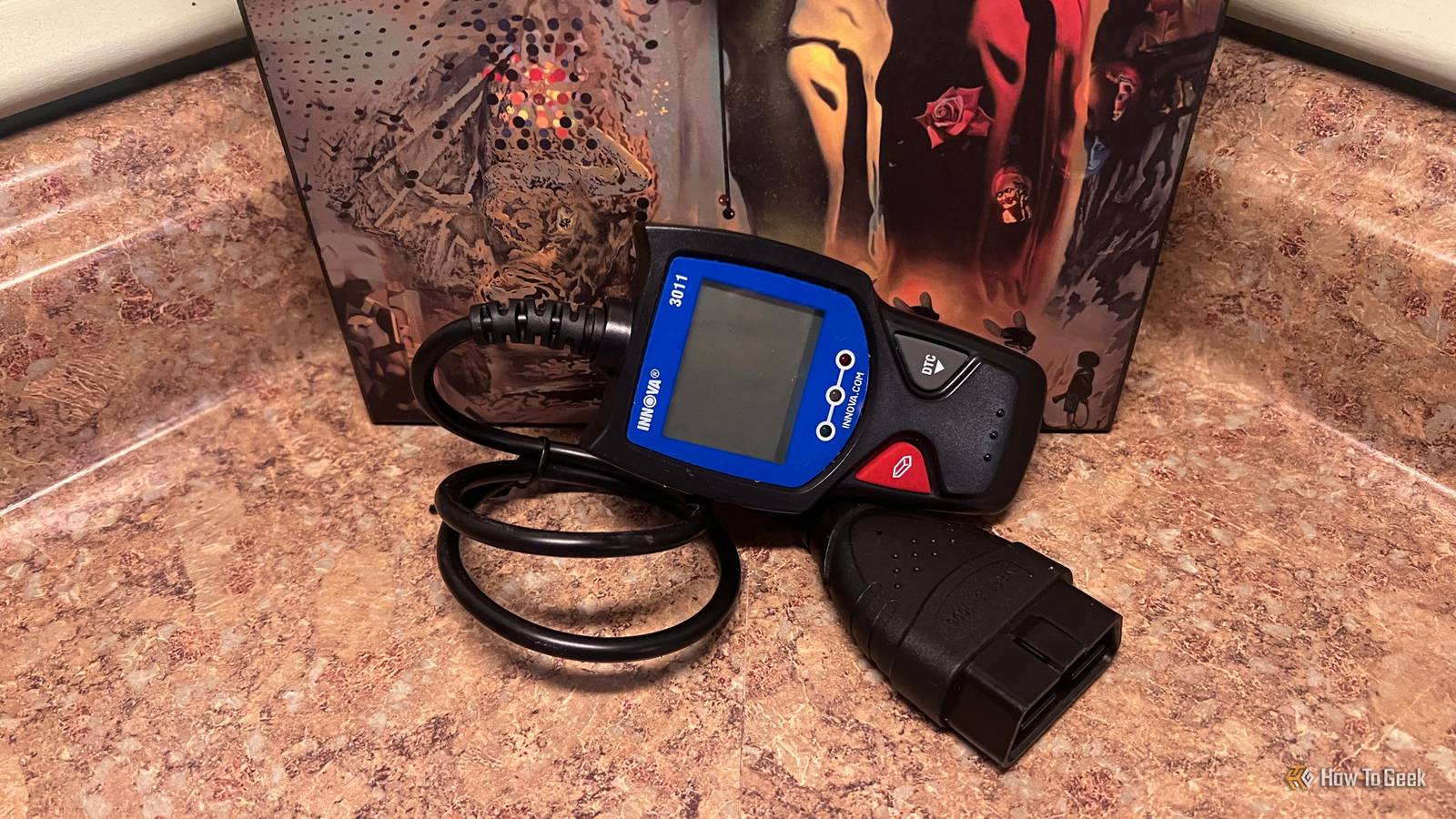 Innova 3011 OBD-II scanner with its diagnostic cable on a countertop.