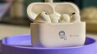 Opened AirPods Pro 3 standing up on a stand with a Memoji on it