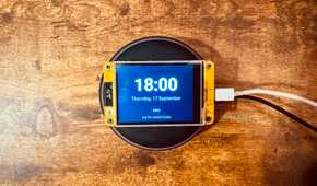 Overhead view of a Cheap Yellow Display mounted on an Echo speaker showing the time and date with a tap for smart home prompt.