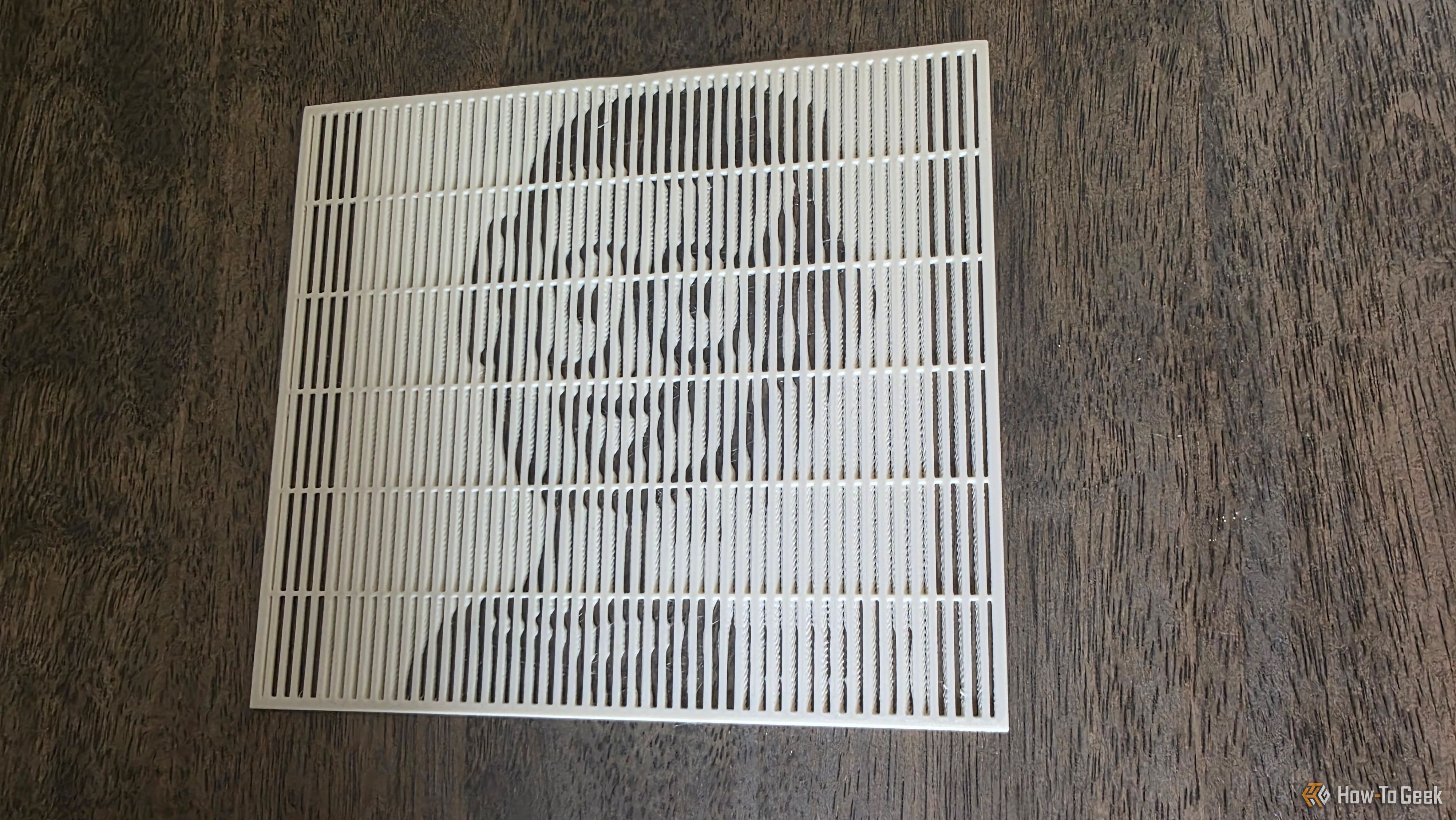 A lenticular 3D print showing the face of the HTG mascot on a brown wooden table.