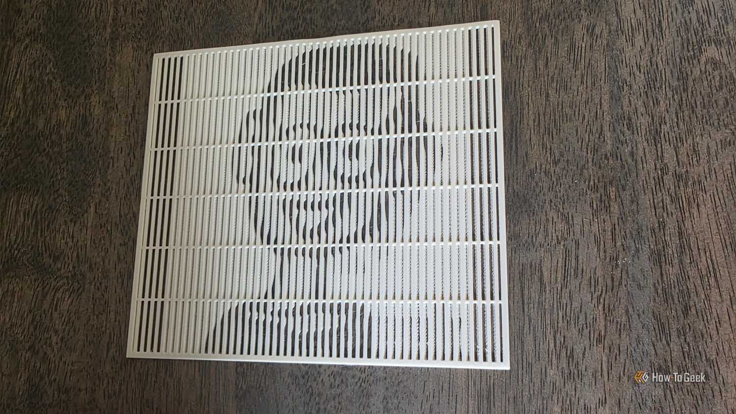 A lenticular 3D print showing the face of the HTG mascot on a brown wooden table.