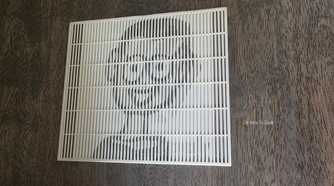 A lenticular 3D print showing the face of the HTG mascot on a brown wooden table.
