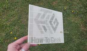 A hand holding a 3D print at a sharp angle, showing the HTG logo.