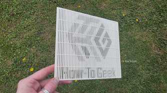 A hand holding a 3D print at a sharp angle, showing the HTG logo.