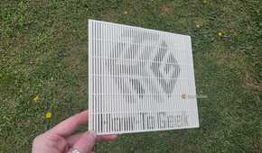 A hand holding a 3D print at a shallow angle, showing the HTG logo.
